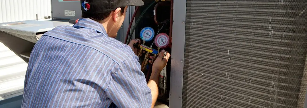 HVAC technician servicing a condenser unit in Carolina Beach